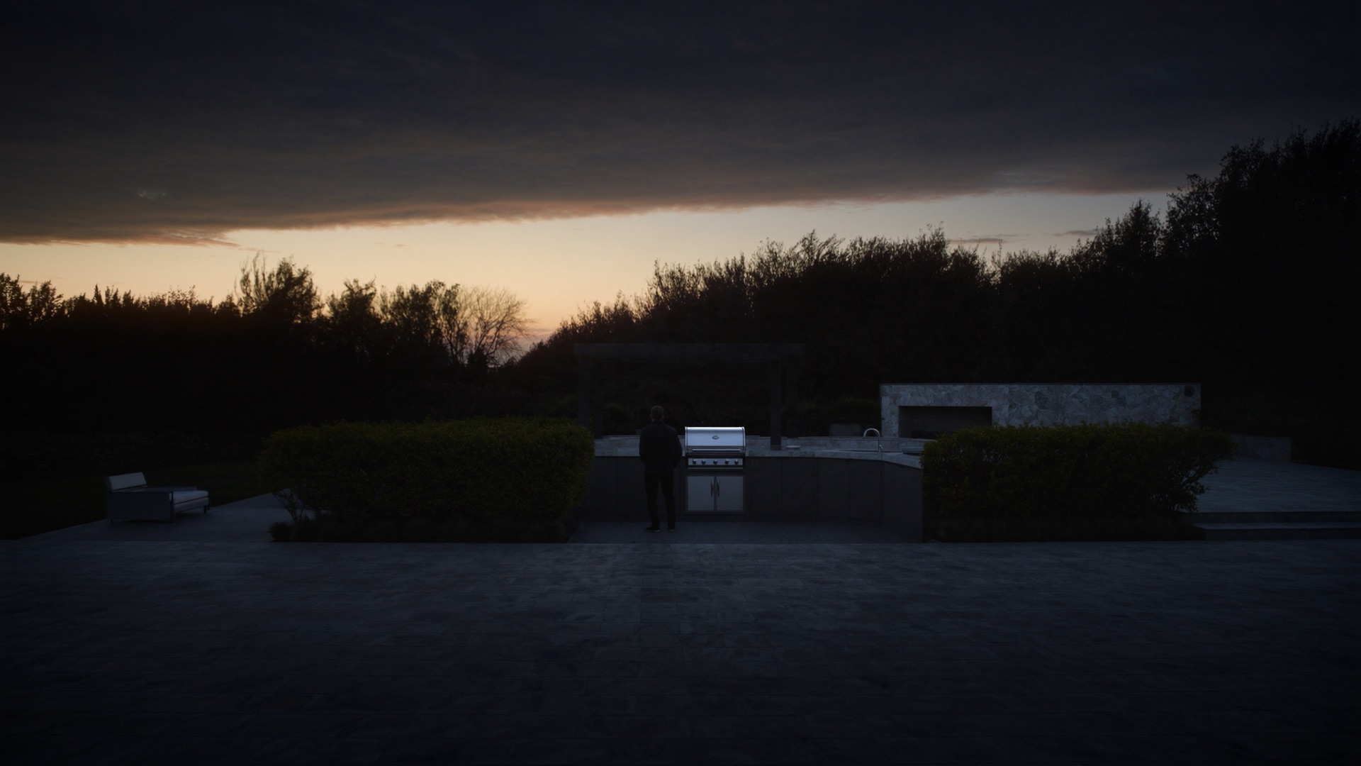 Luxury outdoor kitchen with a stainless grill at dusk.