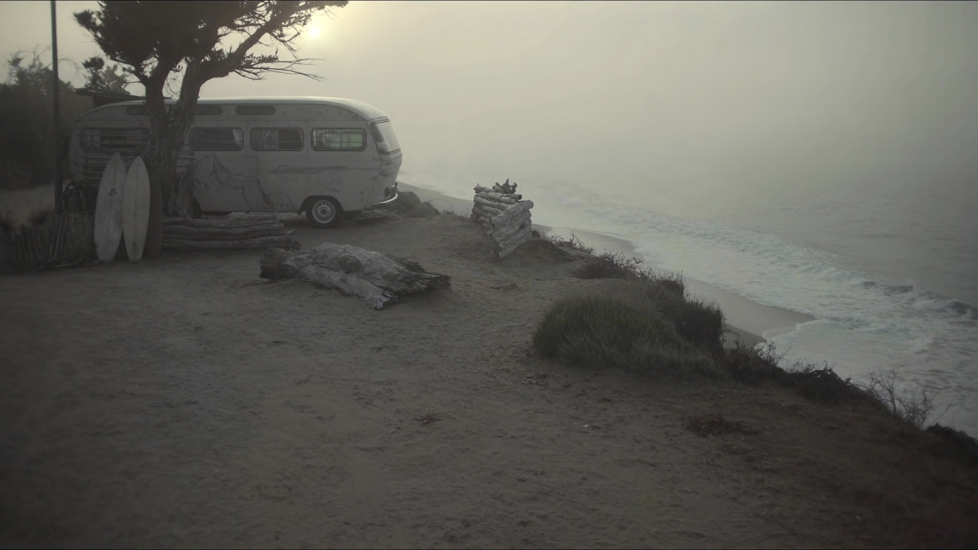 Vintage VW camper van on a foggy Pacific coast at dawn.
